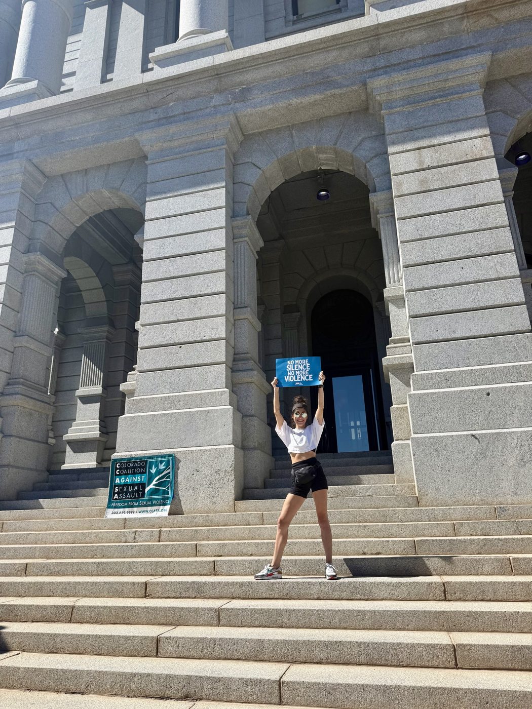 Miranda on the steps of the Colorado State Capitol, holding a sign that reads No More Silence, No More Violence